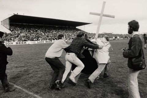 Two members of St John’s College run onto Rugby Park, Hamilton, while two supporters of Springbok Rugby Tour try to stop them, 1981, 1981, Black, Peter (1948– ), Waikato. Purchased 1983 with New Zealand Lottery Board funds. Te Papa